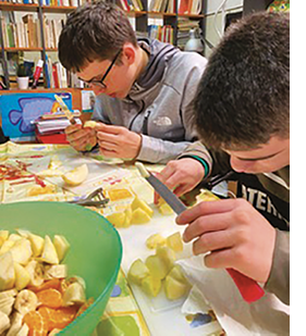 Two teenagers cutting an apple for a fruit salad